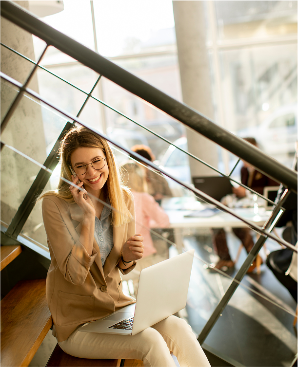 pretty-young-woman-sitting-stairs-with-laptop-using-mobile-phone-modern-office-front-her-team 2
